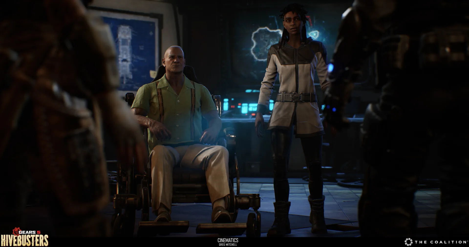 Man seated in a wheelchair beside a standing woman in a dark control room