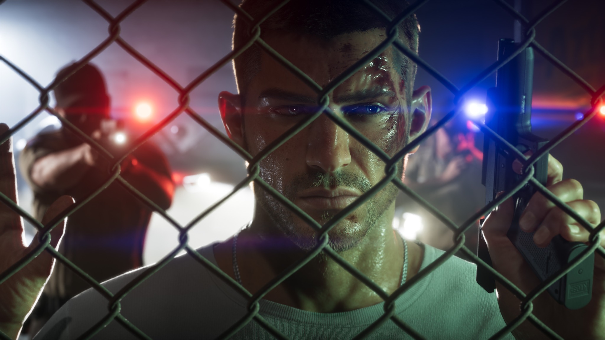 Jason stands behind a chain-link fence with red and blue emergency lights behind him