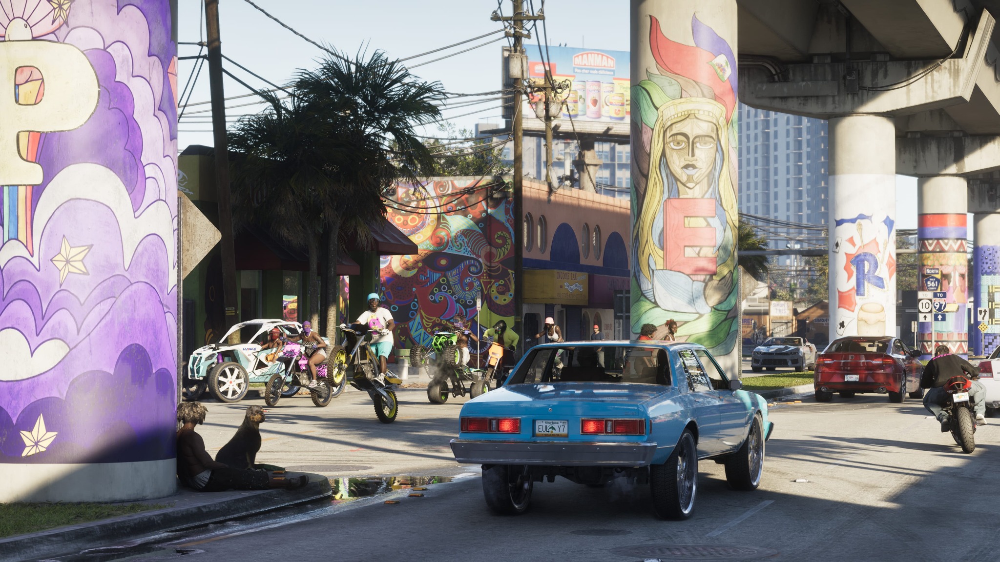 A blue car passes colourful murals on concrete columns beneath an elevated roadway